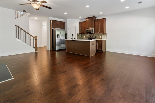 kitchen featuring decorative backsplash, appliances with stainless steel finishes, ceiling fan, sink, and a center island