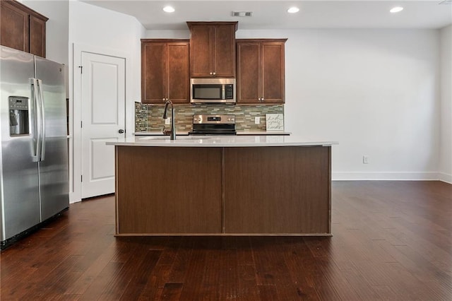 kitchen with backsplash, a kitchen island with sink, sink, dark hardwood / wood-style floors, and appliances with stainless steel finishes