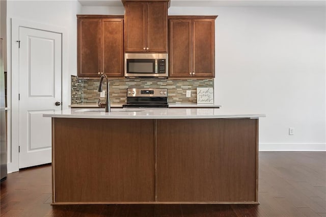 kitchen featuring appliances with stainless steel finishes, tasteful backsplash, a kitchen island with sink, and sink