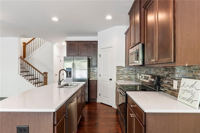 kitchen with tasteful backsplash, stainless steel appliances, dark wood-type flooring, sink, and a center island with sink