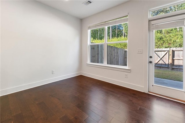 spare room featuring dark hardwood / wood-style floors and a healthy amount of sunlight