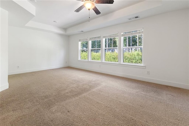 empty room featuring carpet, ceiling fan, and a raised ceiling