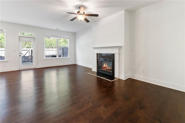 unfurnished living room with ceiling fan and dark wood-type flooring