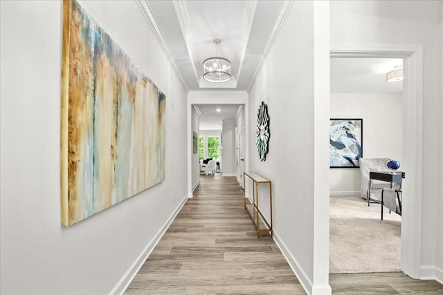 hallway featuring an inviting chandelier, crown molding, and light hardwood / wood-style floors