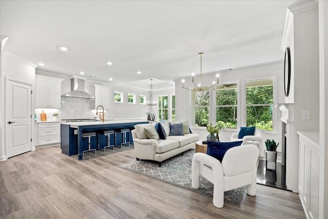 living room with crown molding, light hardwood / wood-style floors, and a chandelier