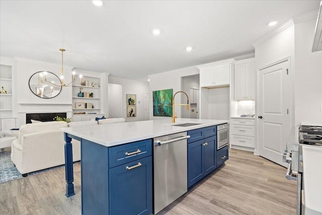 kitchen featuring blue cabinetry, appliances with stainless steel finishes, an island with sink, white cabinets, and decorative light fixtures