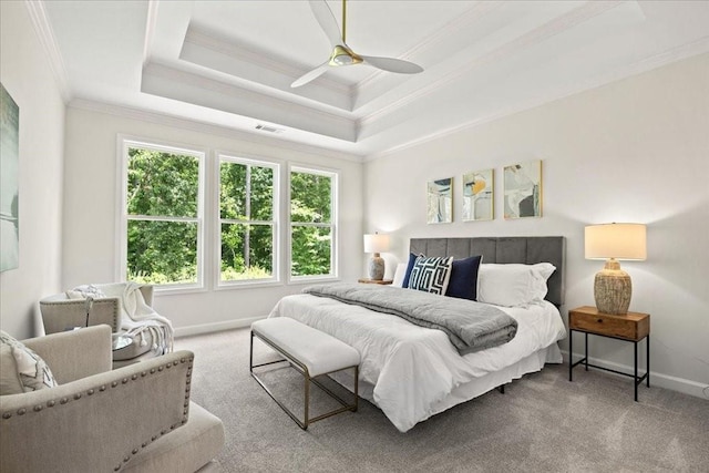 carpeted bedroom featuring a raised ceiling, ornamental molding, and ceiling fan