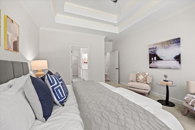 bedroom with light colored carpet, ornamental molding, a tray ceiling, and connected bathroom