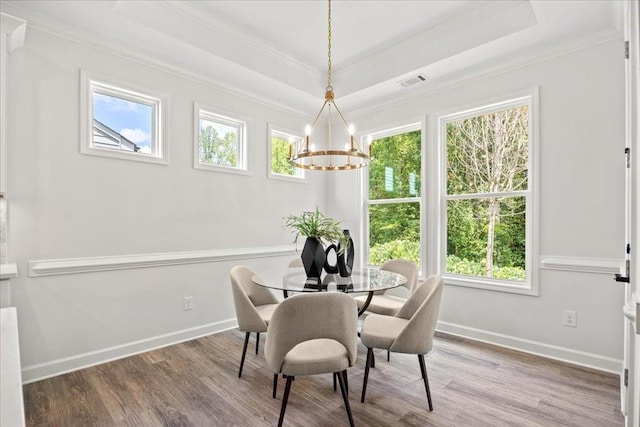 dining space featuring a raised ceiling, wood-type flooring, a healthy amount of sunlight, and crown molding