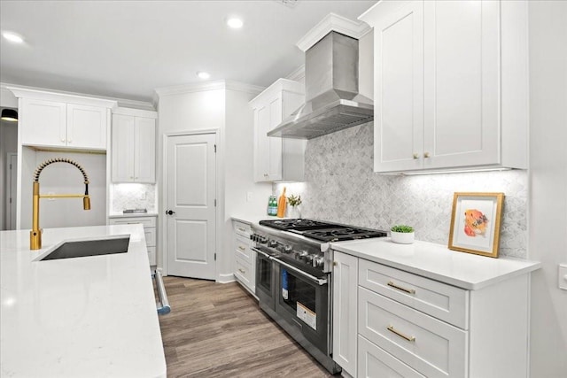 kitchen featuring white cabinets, double oven range, sink, and wall chimney range hood