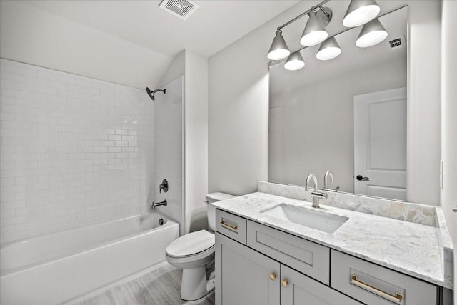 full bathroom featuring tiled shower / bath combo, vanity, wood-type flooring, and toilet