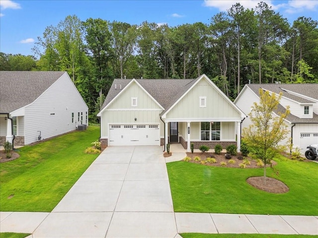 view of front of home with cooling unit, a garage, a front yard, and covered porch