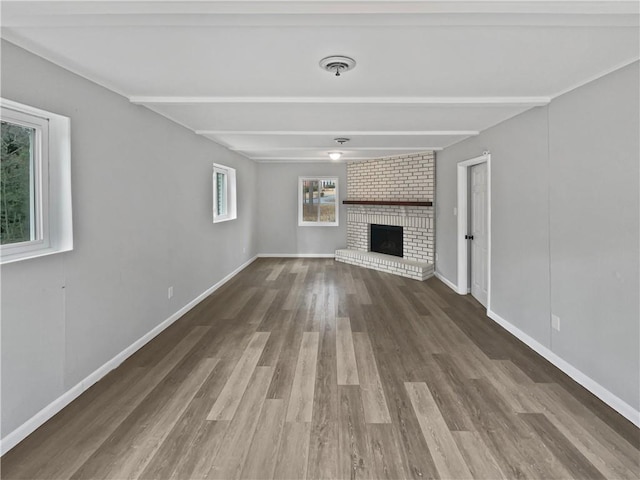 unfurnished living room with beamed ceiling, a fireplace, and dark hardwood / wood-style flooring