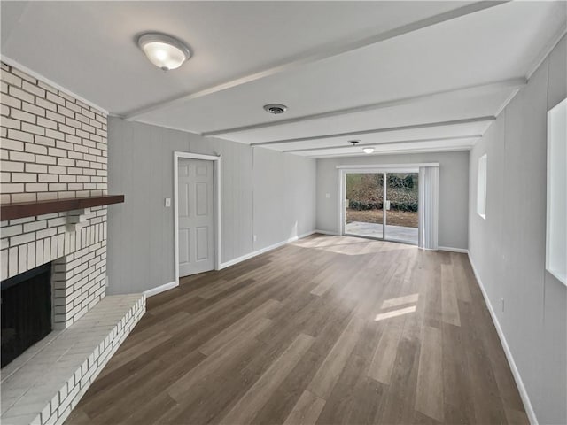 unfurnished living room with beam ceiling, hardwood / wood-style floors, and a fireplace