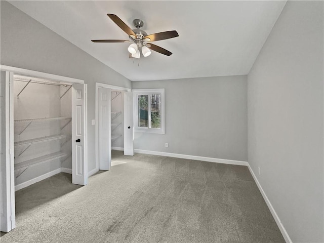 unfurnished bedroom featuring dark colored carpet, vaulted ceiling, and ceiling fan