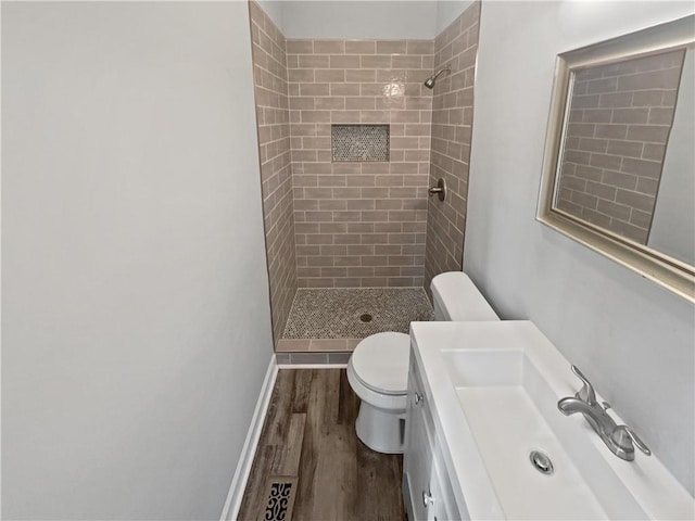 bathroom featuring vanity, toilet, hardwood / wood-style floors, and a tile shower