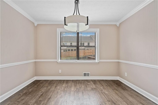 unfurnished dining area featuring crown molding, baseboards, visible vents, and wood finished floors