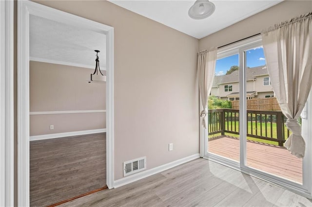 interior space with baseboards, wood finished floors, and visible vents