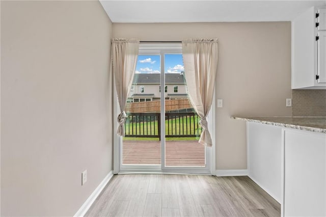 unfurnished dining area featuring baseboards and light wood finished floors