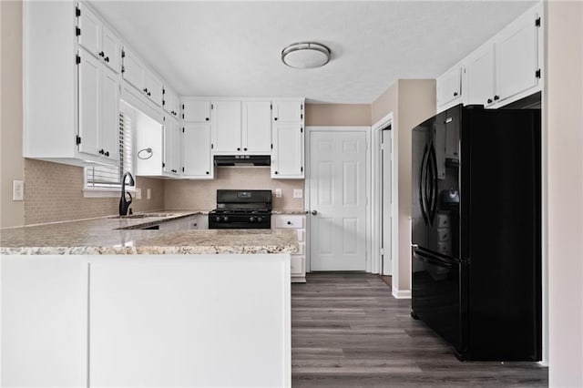 kitchen with dark wood-style flooring, a sink, a peninsula, under cabinet range hood, and black appliances