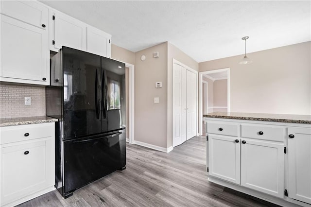 kitchen with freestanding refrigerator, decorative backsplash, light wood-style floors, baseboards, and white cabinets