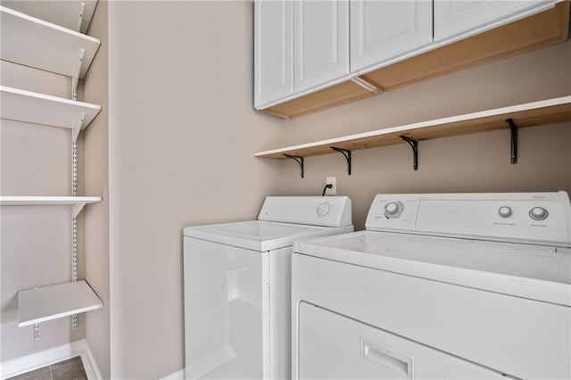 washroom with baseboards, cabinet space, and washer and dryer