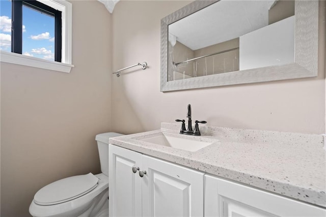 bathroom featuring vanity, walk in shower, and toilet