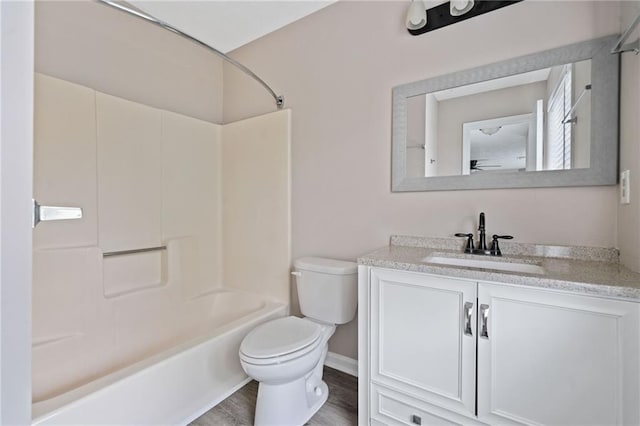 full bath featuring wood finished floors, vanity, baseboards, toilet, and  shower combination