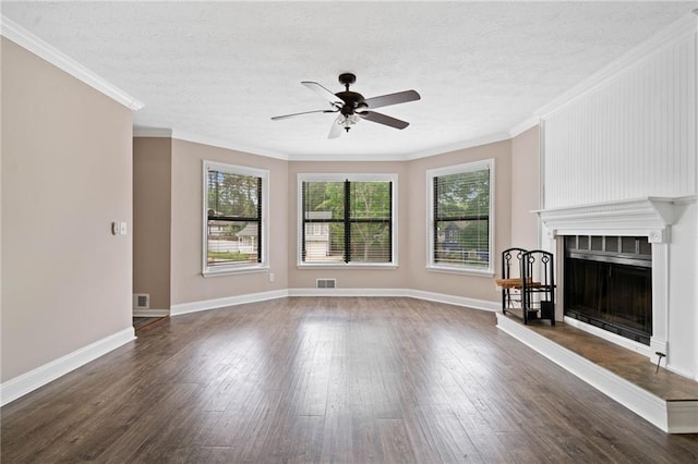 unfurnished living room with plenty of natural light, a tiled fireplace, ceiling fan, and wood finished floors