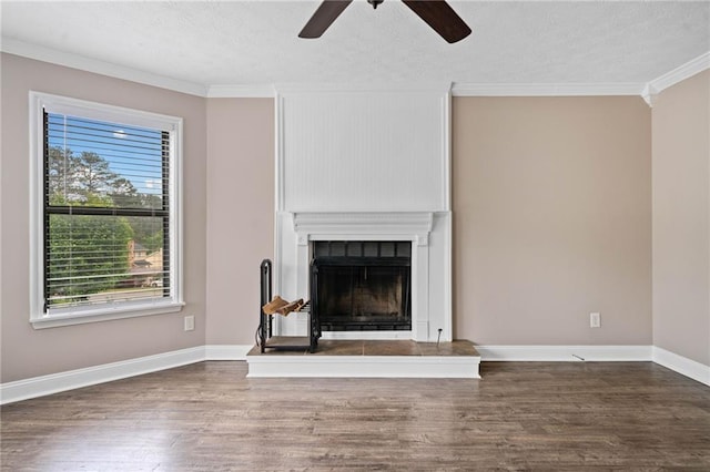 unfurnished living room with crown molding, a ceiling fan, wood finished floors, and a fireplace