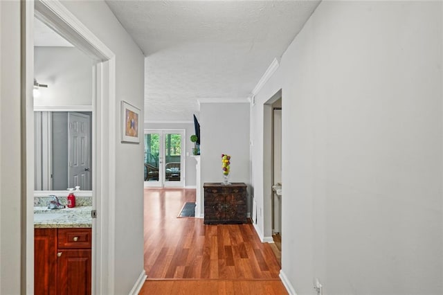 212 Brittany Ct, Duluth, GA 30096 - hall featuring a textured ceiling, wood finished floors, baseboards, crown molding, and a sink