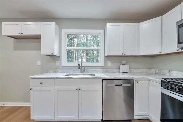 kitchen with stainless steel appliances, white cabinetry, light hardwood / wood-style floors, and sink