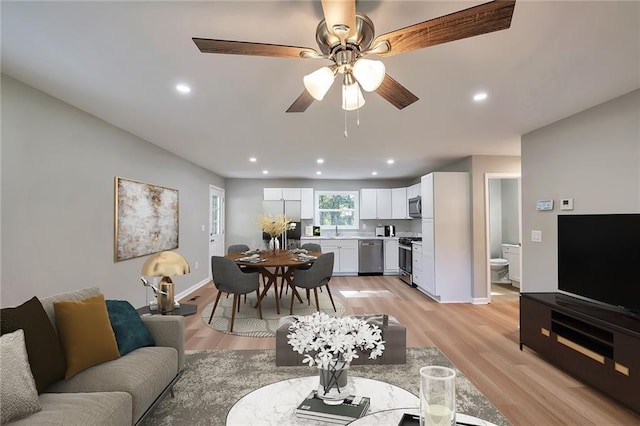 living room featuring ceiling fan, light wood-type flooring, and sink