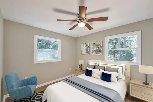 bedroom featuring ceiling fan, dark wood-type flooring, and multiple windows