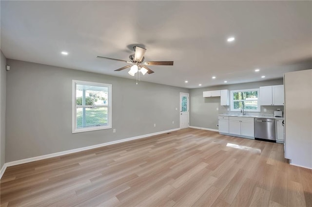 kitchen featuring white cabinetry, stainless steel dishwasher, plenty of natural light, and light hardwood / wood-style flooring