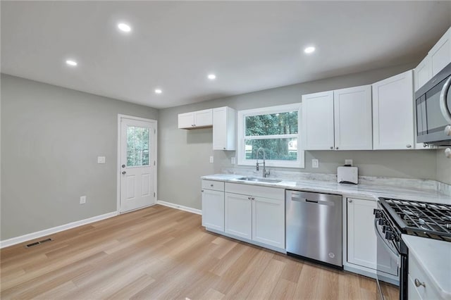 kitchen with white cabinets, stainless steel appliances, a wealth of natural light, and sink