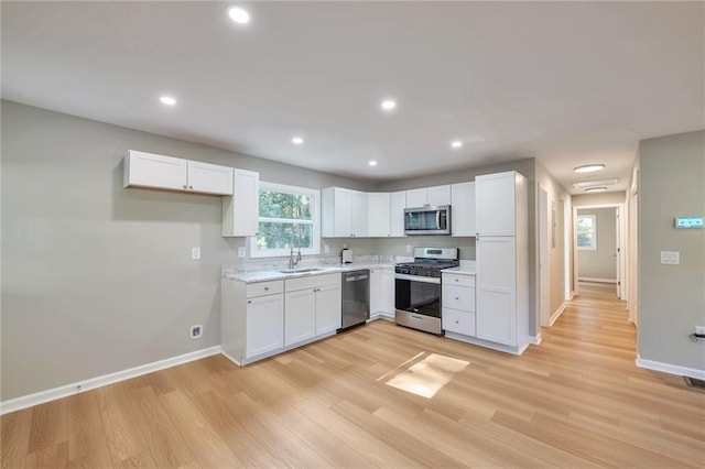 kitchen featuring appliances with stainless steel finishes, light hardwood / wood-style flooring, and white cabinetry