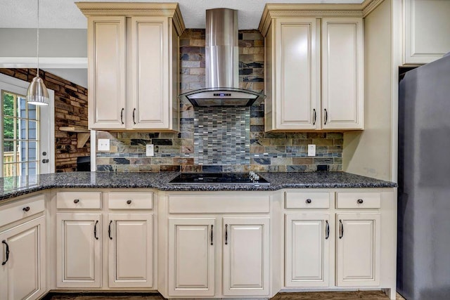 kitchen with freestanding refrigerator, black electric cooktop, wall chimney exhaust hood, backsplash, and decorative light fixtures