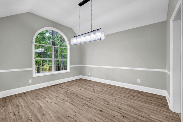 unfurnished dining area with baseboards, a chandelier, wood finished floors, and vaulted ceiling