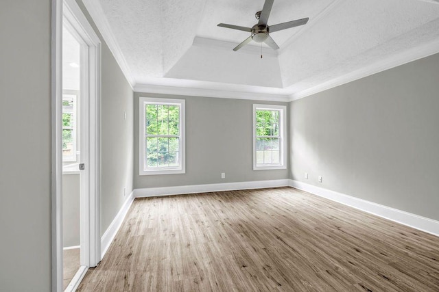 unfurnished room with crown molding, a tray ceiling, baseboards, and wood finished floors