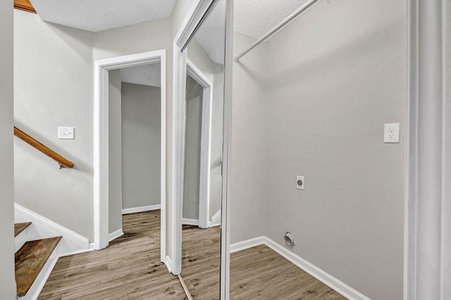 clothes washing area with baseboards, electric dryer hookup, light wood-style flooring, and laundry area