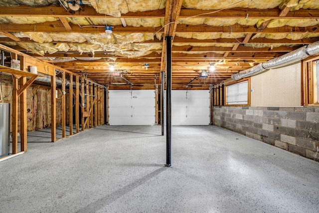 garage with a garage door opener, water heater, and concrete block wall