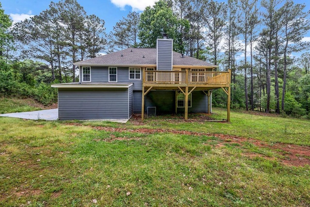 rear view of house featuring a yard, a wooden deck, roof with shingles, and a chimney