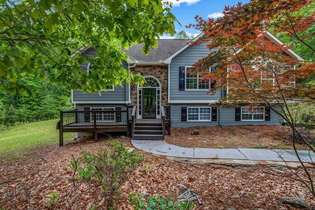 bi-level home featuring a wooden deck and a shingled roof