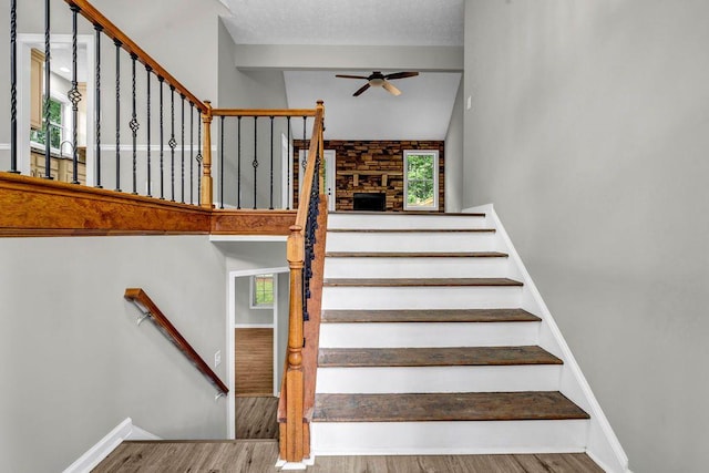 staircase featuring baseboards, ceiling fan, a healthy amount of sunlight, and wood finished floors