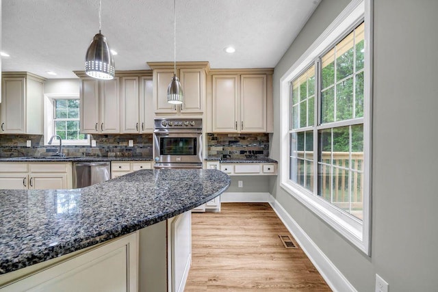 kitchen featuring hanging light fixtures, tasteful backsplash, baseboards, light wood-type flooring, and stainless steel dishwasher