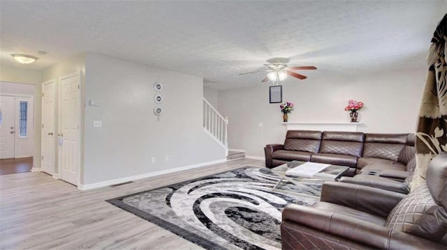 living room featuring ceiling fan, a textured ceiling, and light hardwood / wood-style flooring