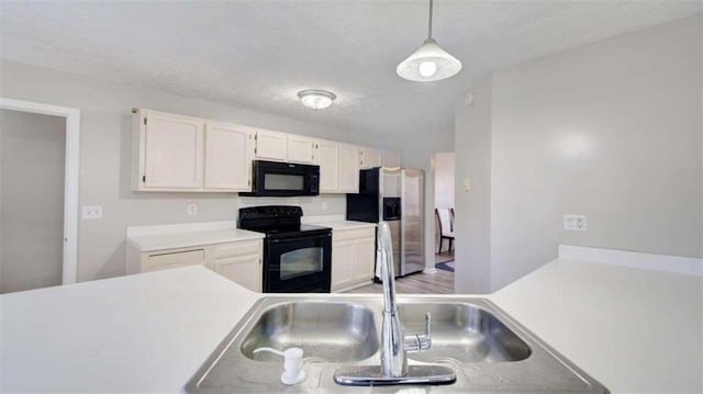 kitchen with black appliances, sink, hanging light fixtures, light wood-type flooring, and white cabinetry