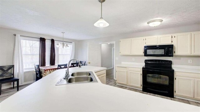 kitchen featuring sink, hanging light fixtures, a chandelier, light hardwood / wood-style floors, and black appliances