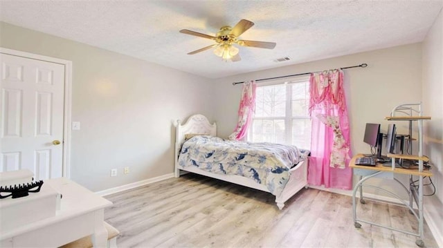 bedroom with hardwood / wood-style floors, ceiling fan, and a textured ceiling